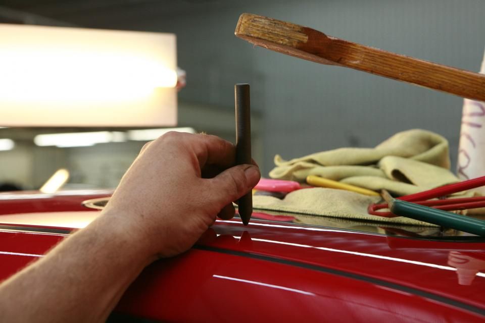 Mains qui contrôlent la carrosserie rouge d'une voiture en atelier