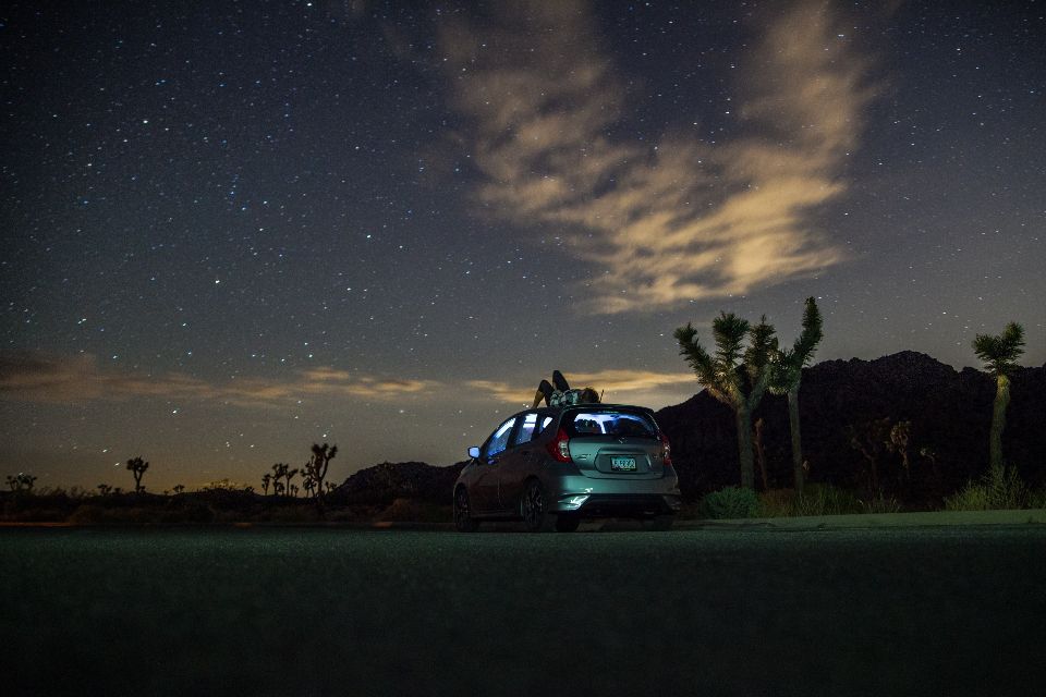 Voiture garée de nuit sous un ciel étoilé